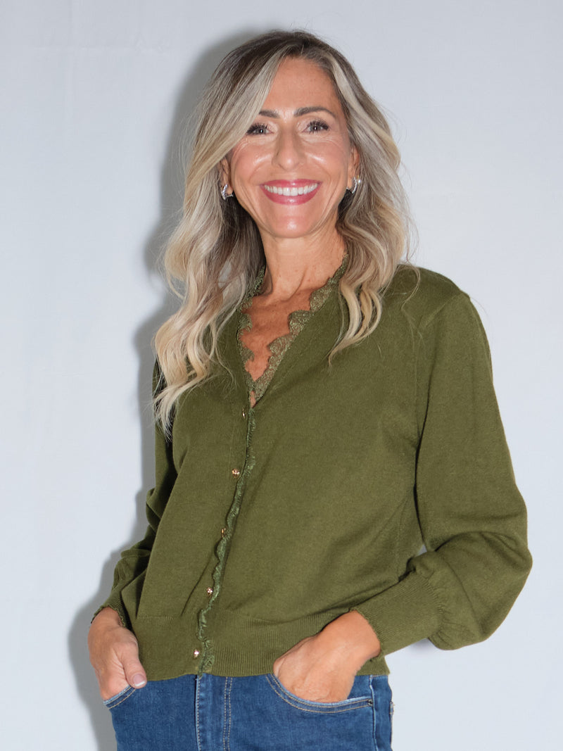 Cardigan bordato in pizzo in colore olio indossato da donna sorridente con capelli lunghi.