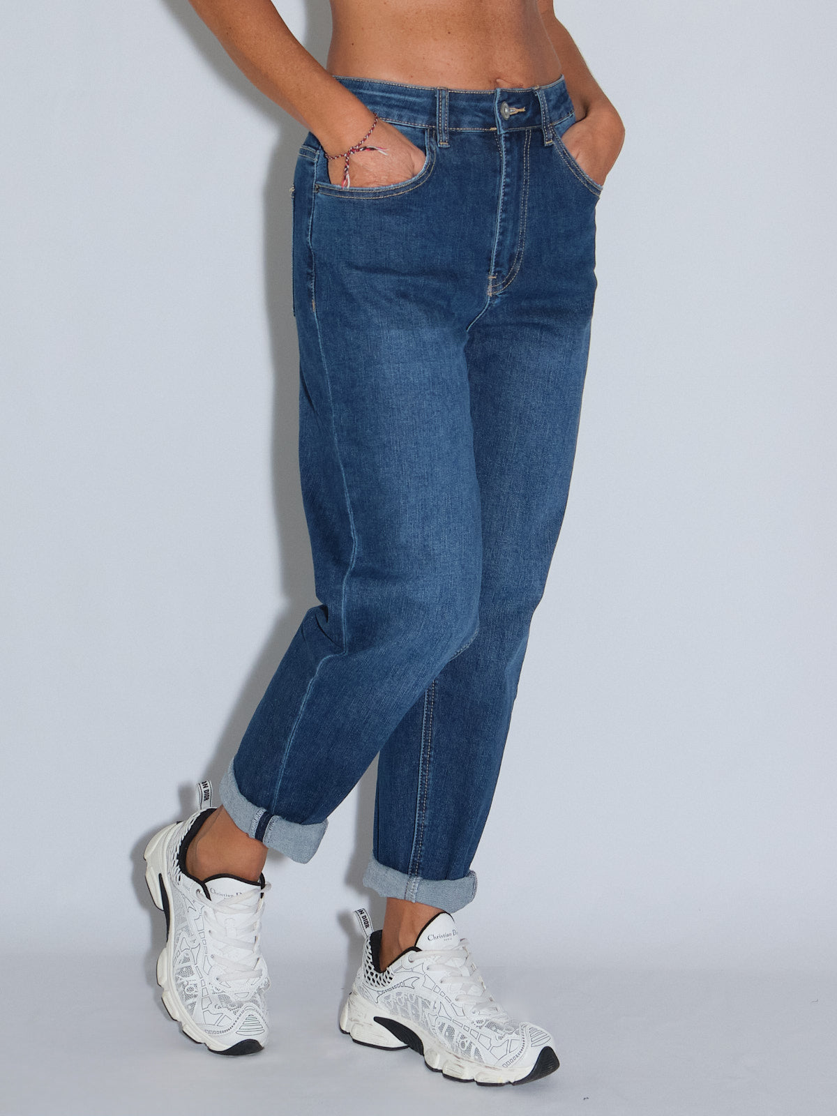 Jeans gamba dritta in lavaggio blu scuro, elasticizzati e con vita alta, indossati con sneakers bianche.
