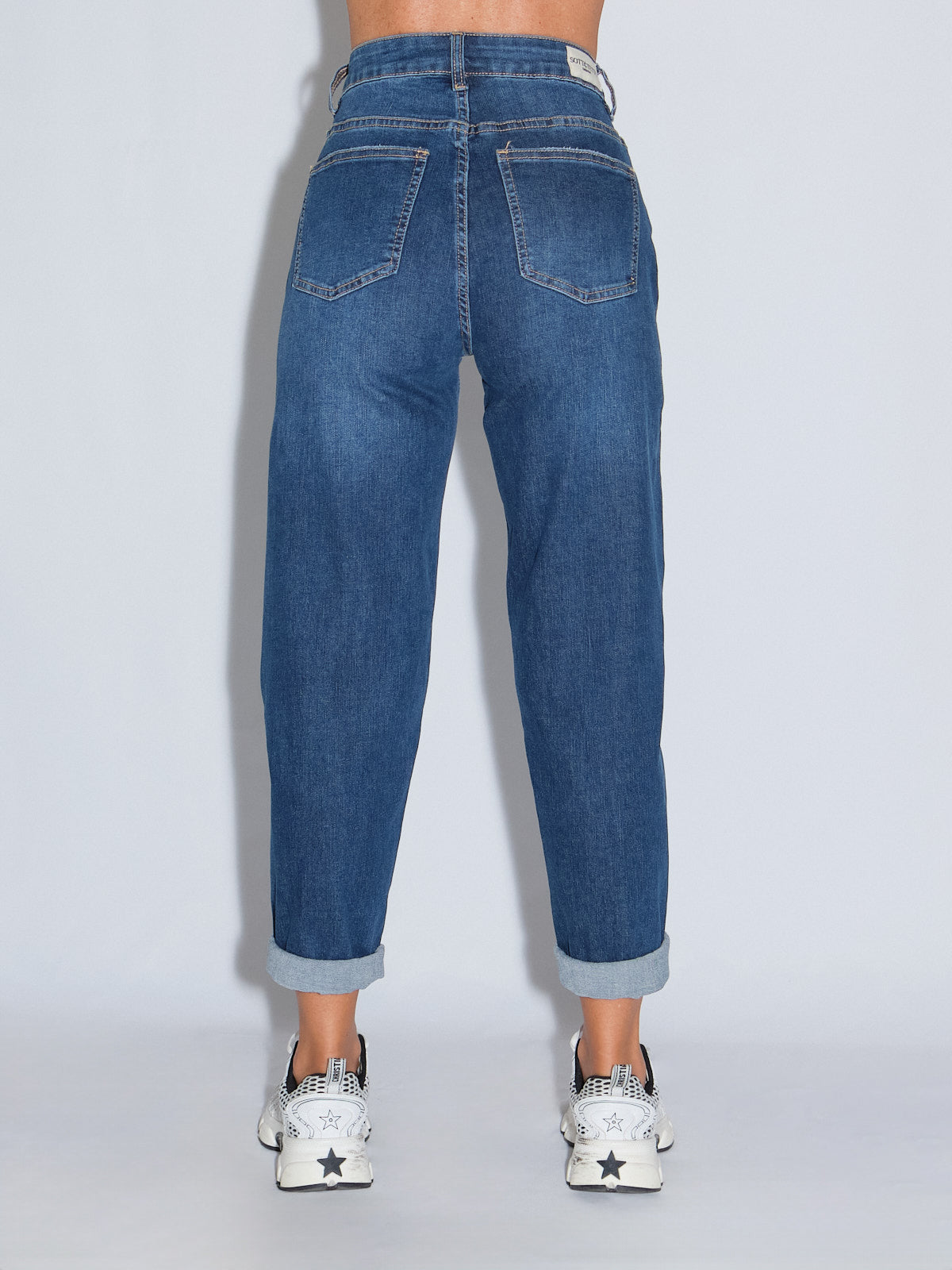 Jeans gamba dritta, lavaggio blu scuro, dal retro, con vita alta e fit speciale, abbinati a scarpe sportive.