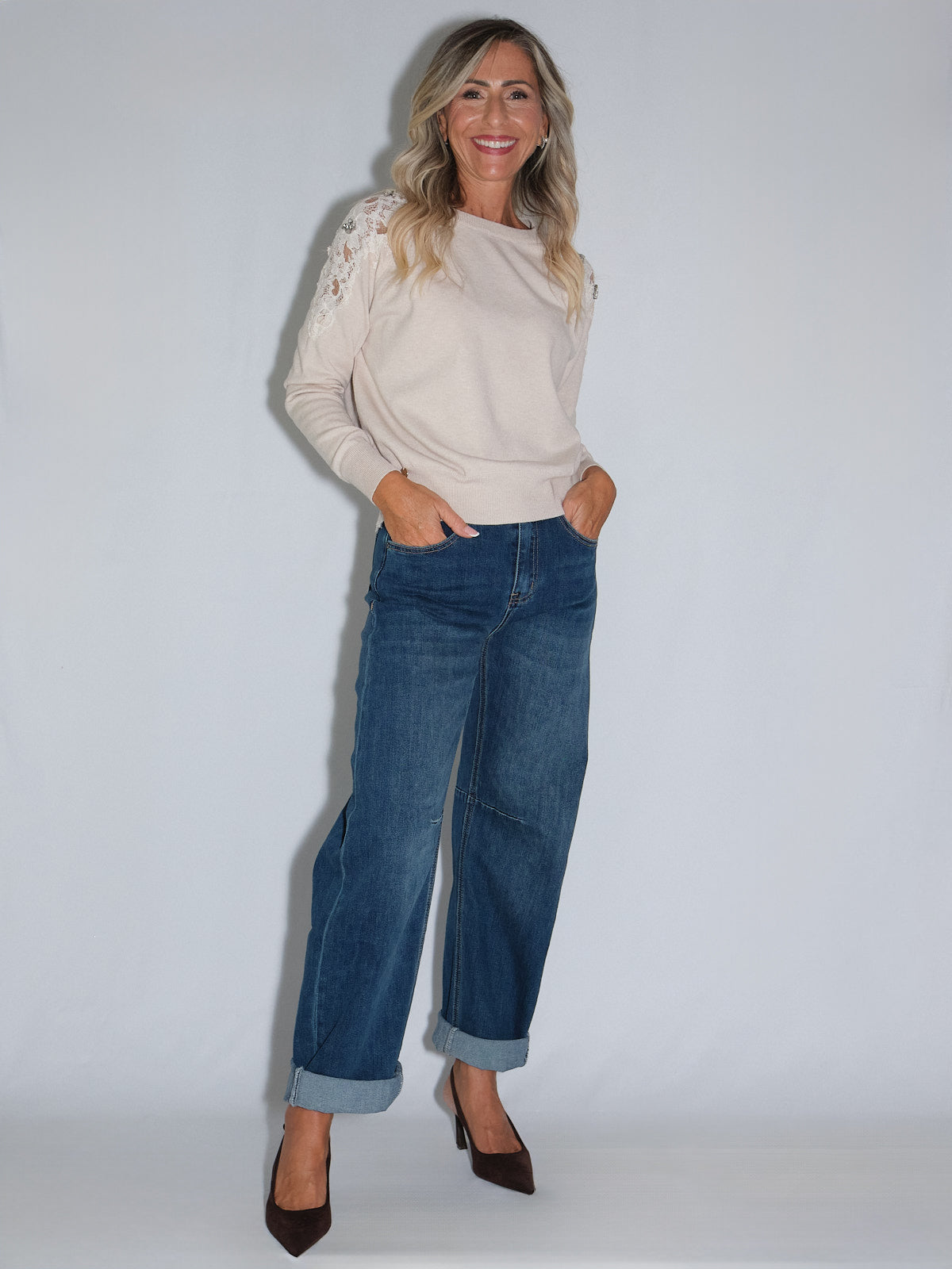 Modella che indossa una maglia con inserti in pizzo sulle spalle e jeans larghi, elegante e casual.