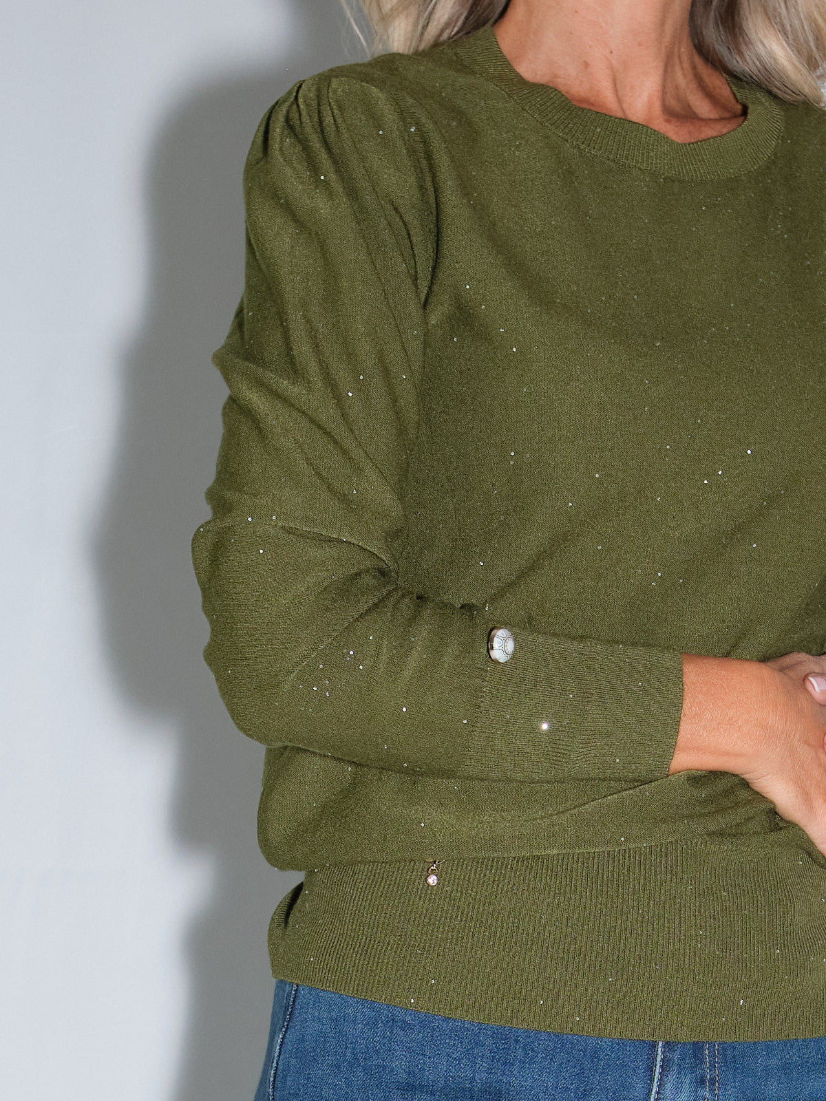 Girocollo manica lunga lurex in colore olio con dettagli scintillanti e bottoncini sui polsi.
