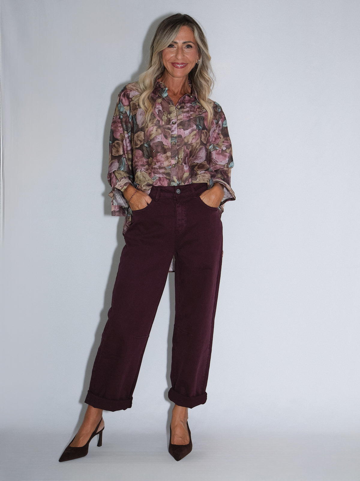 Donna in soffice camicia floreale e pantalone effetto balloon prugna con tacchi alti.