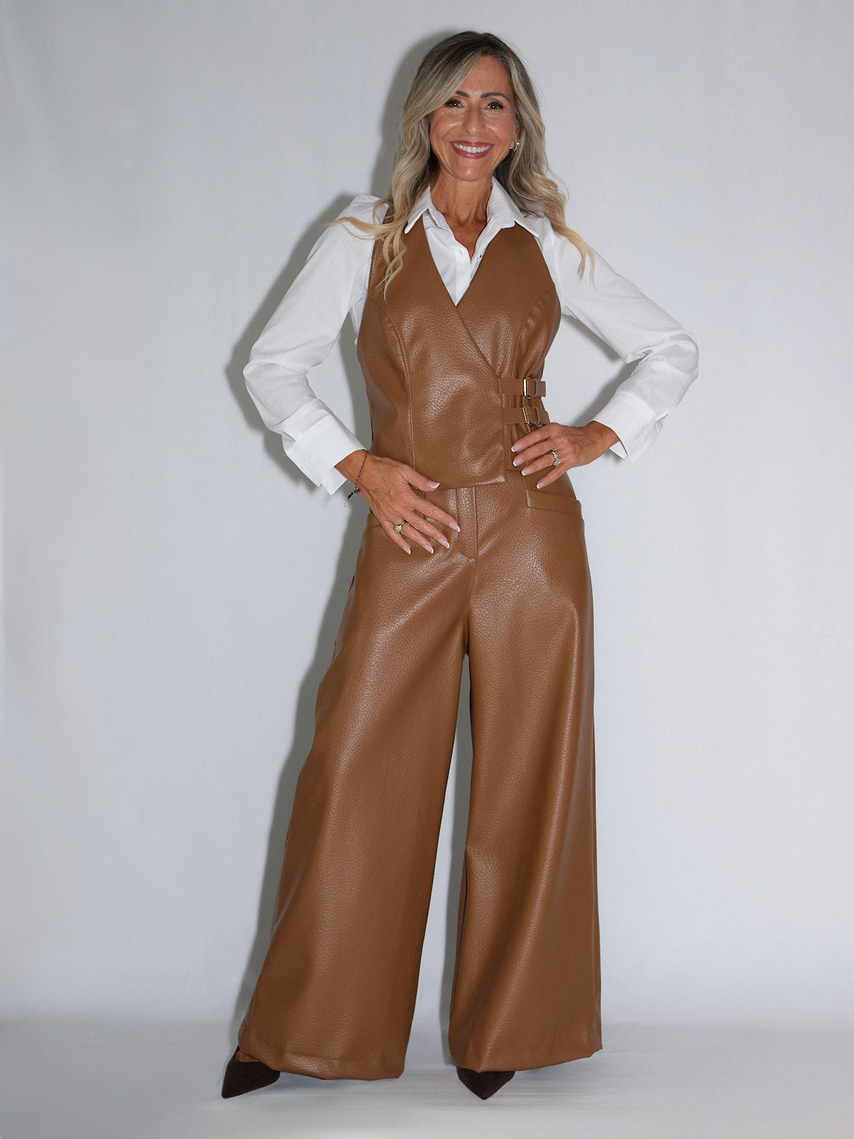 Pantalone palazzo in eco pelle, modello con vita alta, abbinato a un gilet, per un outfit stiloso e di tendenza.