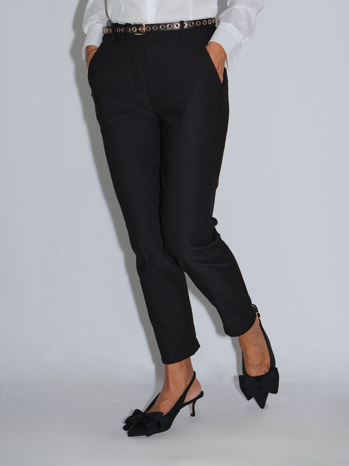 Pantalone a sigaretta neri con elastico in vita, abbinati a una camicia bianca e scarpe eleganti con tacco.