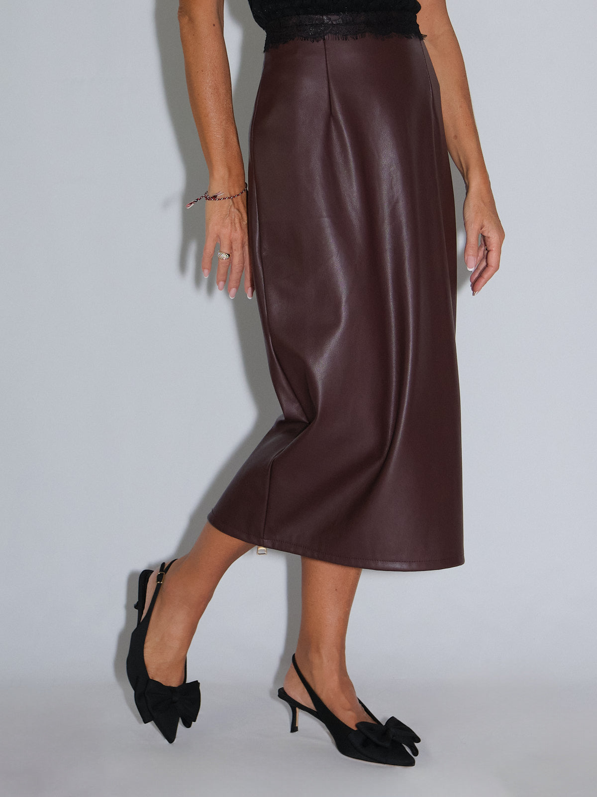Tubino in ecopelle bordeaux indossato con scarpe nere eleganti, stile rock-chic per la stagione.