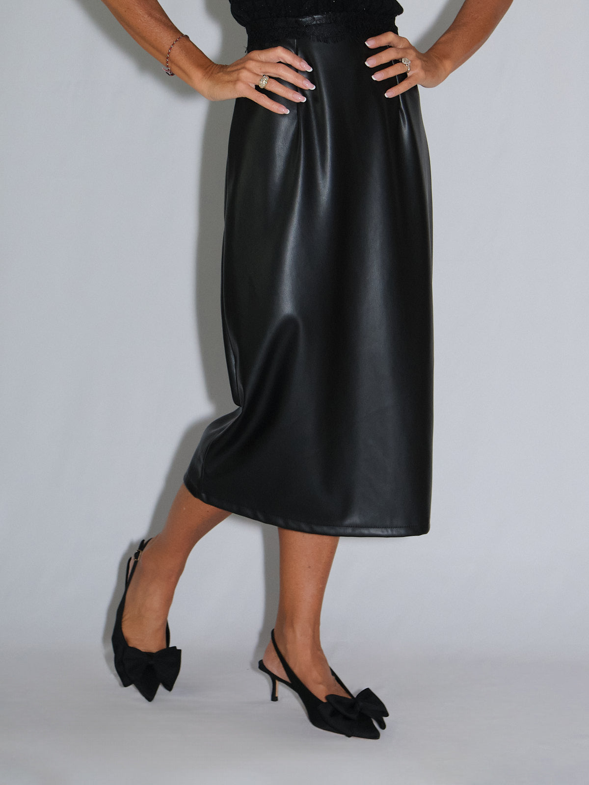 Model wearing a black Tubino in ecopelle skirt with stylish black bow heels.