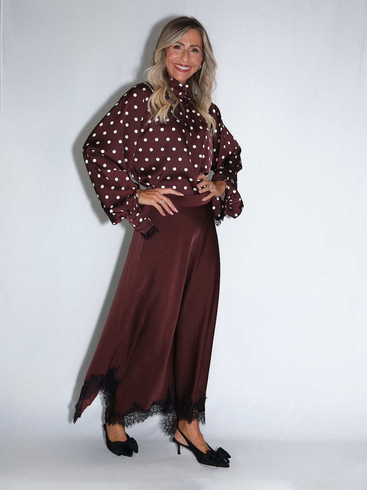 Gonna a ruota con pizzo indossata con blusa a pois bordeaux, look elegante e fluido.
