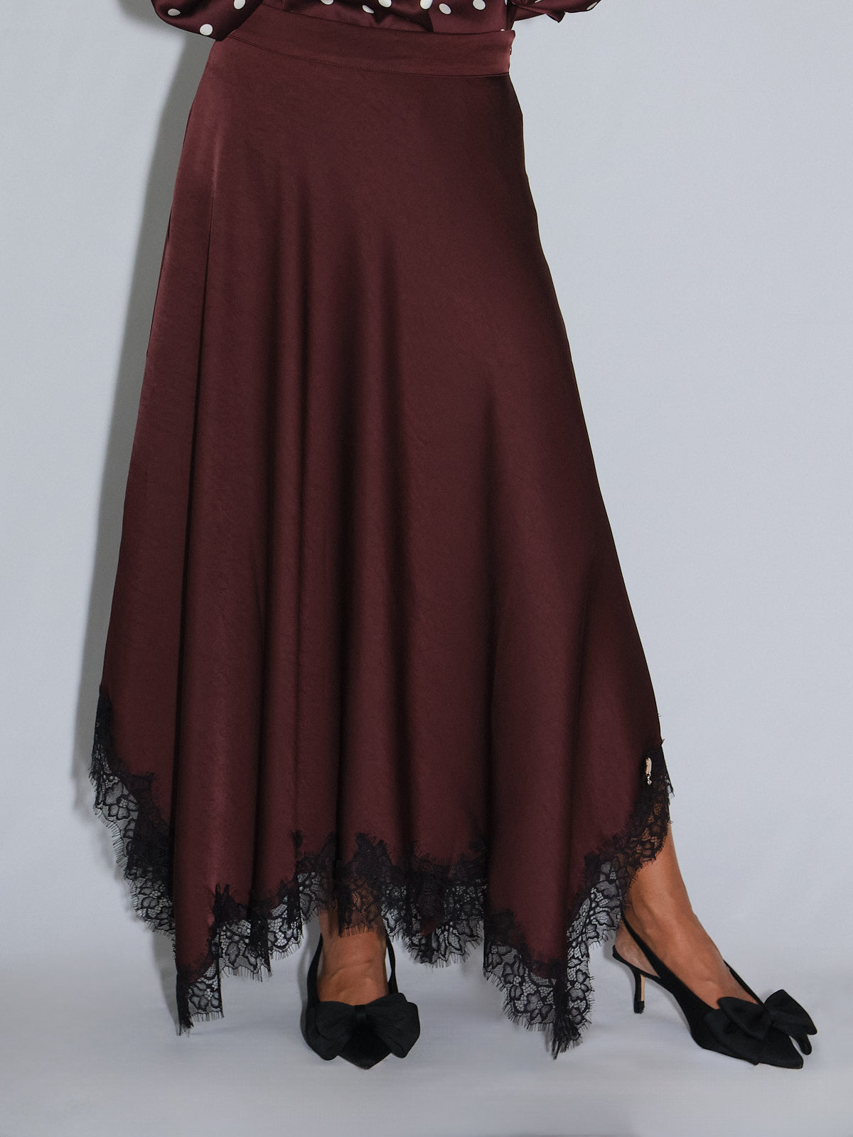 Gonna a ruota con pizzo nera, outfit elegante con taglio fluido e morbido, abbinata a blusa a pois bordeaux.