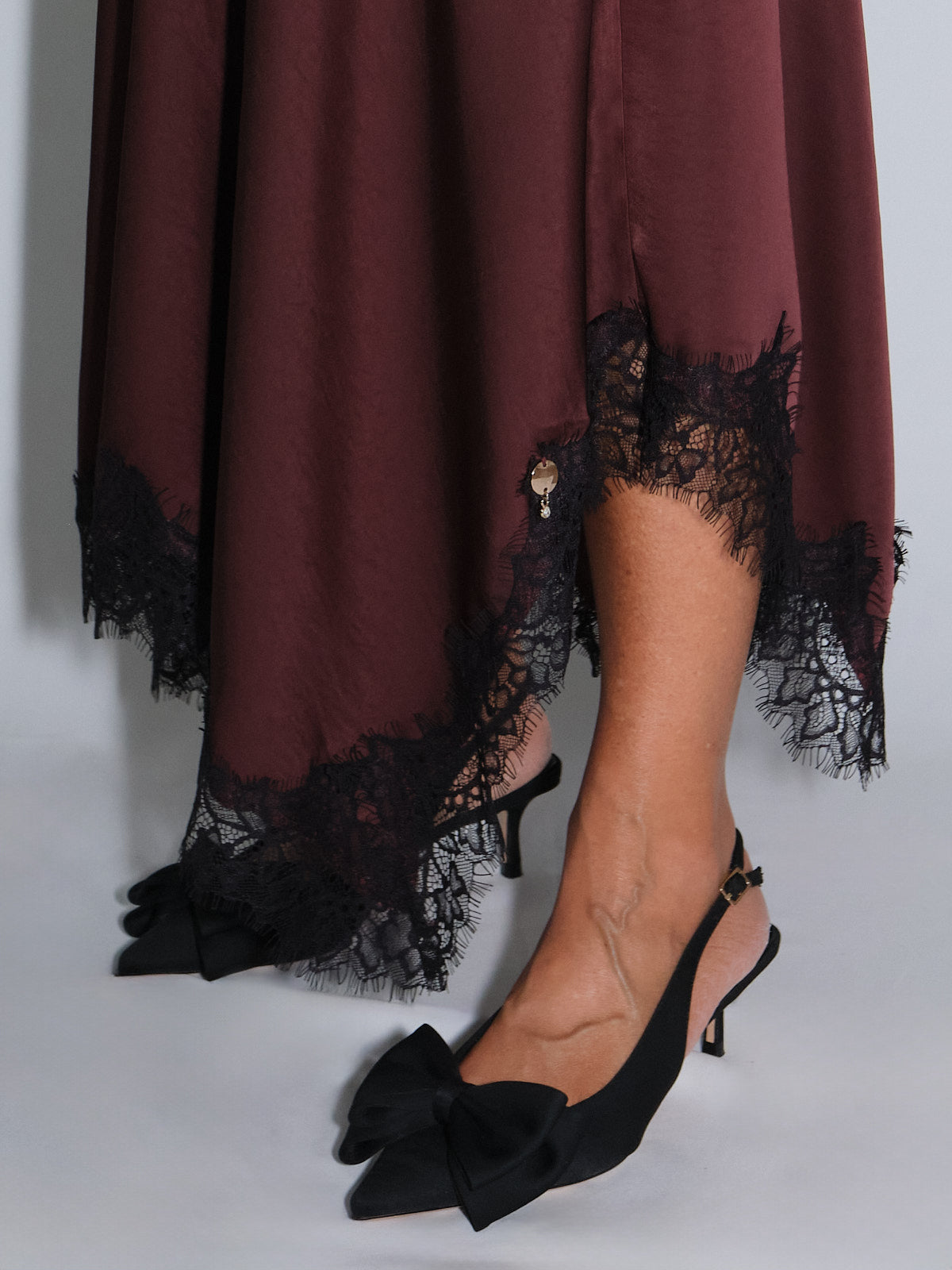 Gonna a ruota con pizzo nero e balza, indossata con scarpe con tacco e fiocco, look elegante e raffinato.